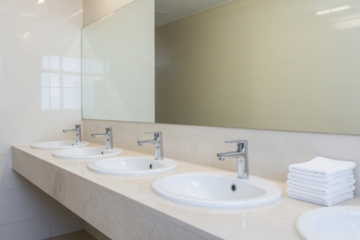A spotless commercial restroom with dry sinks and stacked towels